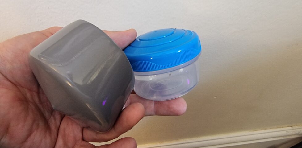 A small plastic screw-top tub and post topper; components for the geocache.