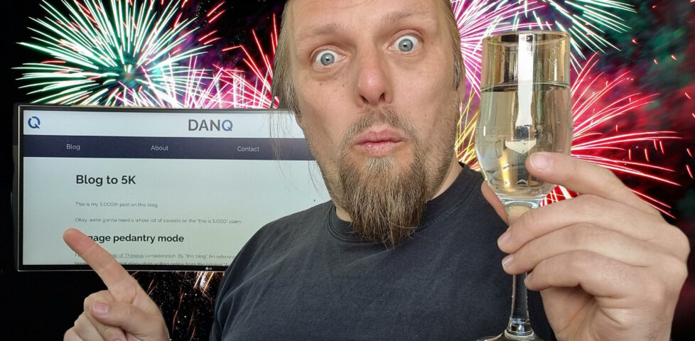 Dan with a champagne flute, fireworks in the background, points to a screen showing this blog post.
