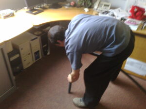 Gareth sucks water out from under a desk using a vacuum cleaner, #2.