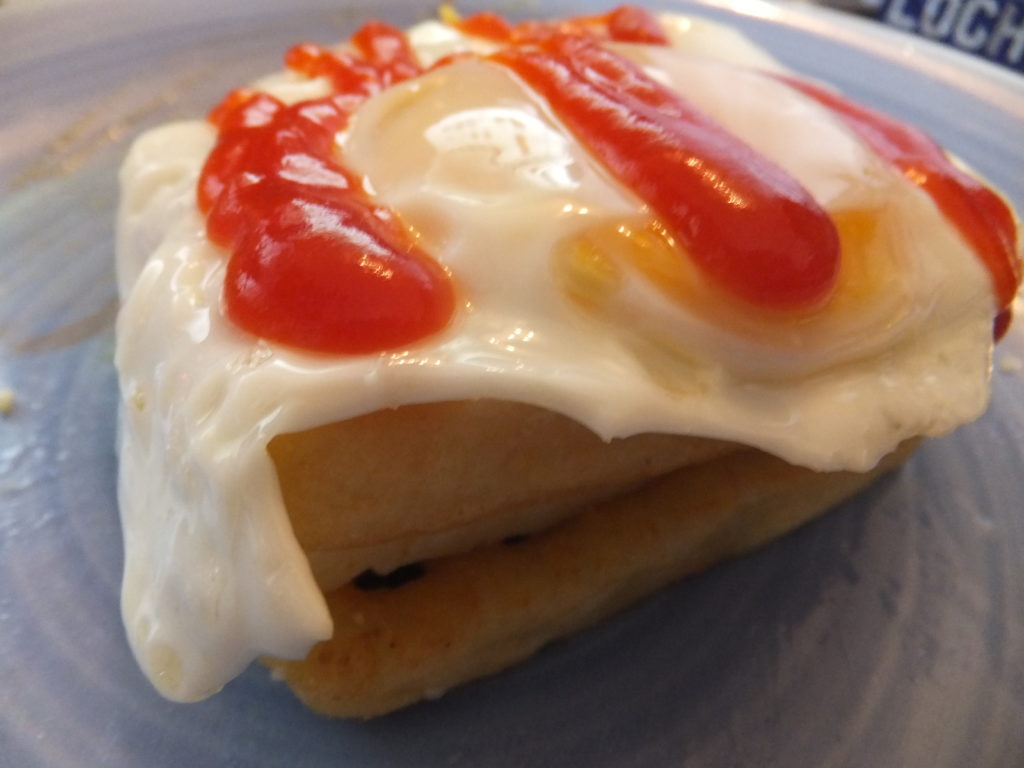 From bottom to top: potato waffle, cheese, potato waffle, egg, tomato ketchup.