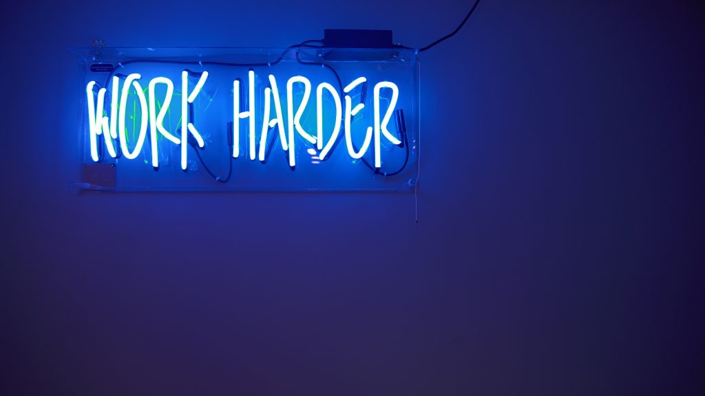 Neon sign showing the words "Work Harder"