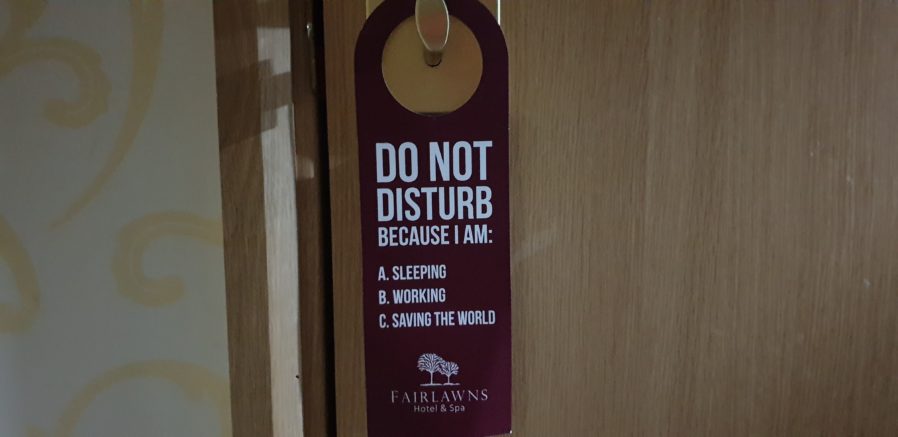 Do Not Disturb sign with reasons: Sleeping, Working, Saving the World.