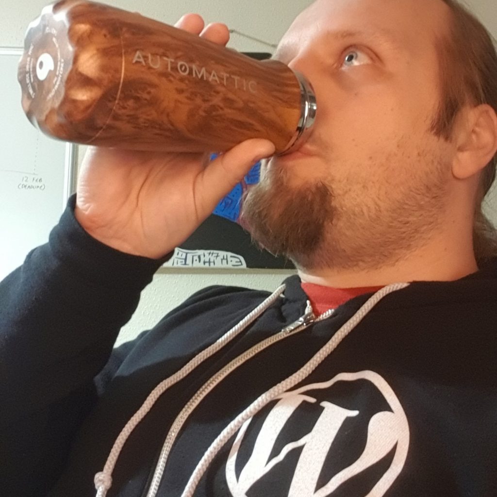 Dan wearing a WordPress hoodie and drinking from an Automattic bottle.