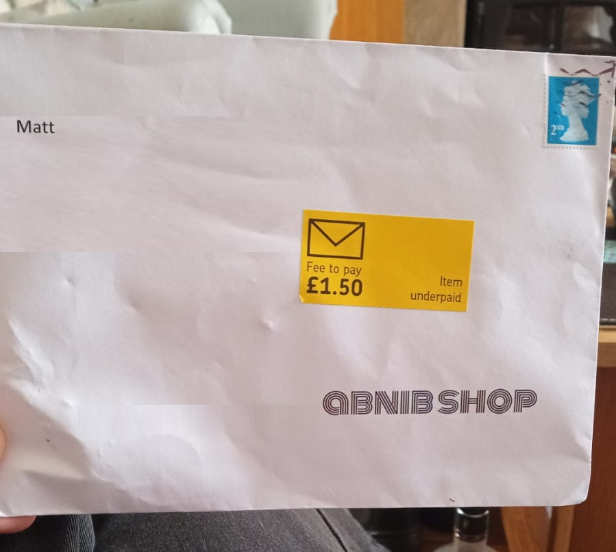 C5 envelope with a yellow "Item underpaid. Fee to pay £1.50" sticker attached.
