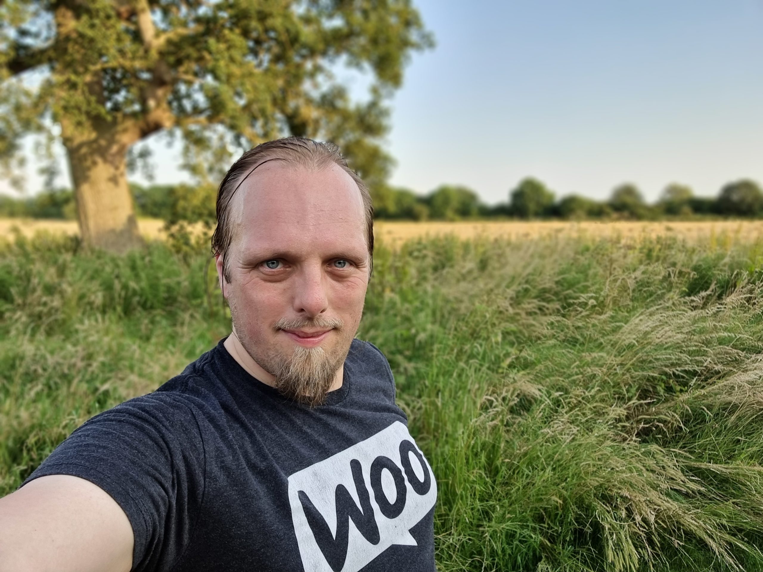 Selfie of Dan standing by a tree in a freshly-mowed cornfield.