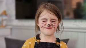 A girl with felt-tip whiskers drawn on to look like a cat.