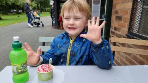 A boy enjoys an ice cream at a park cafe.