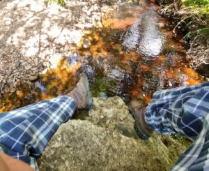Orange-red river water beneath Dan's feet.