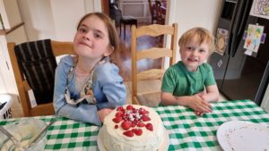 The kids pose with a fruit-topped cake.