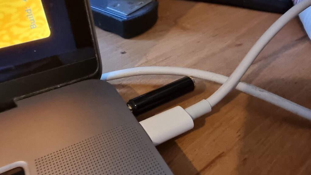 3.5mm adapter plugged into the headphone port on a laptop.
