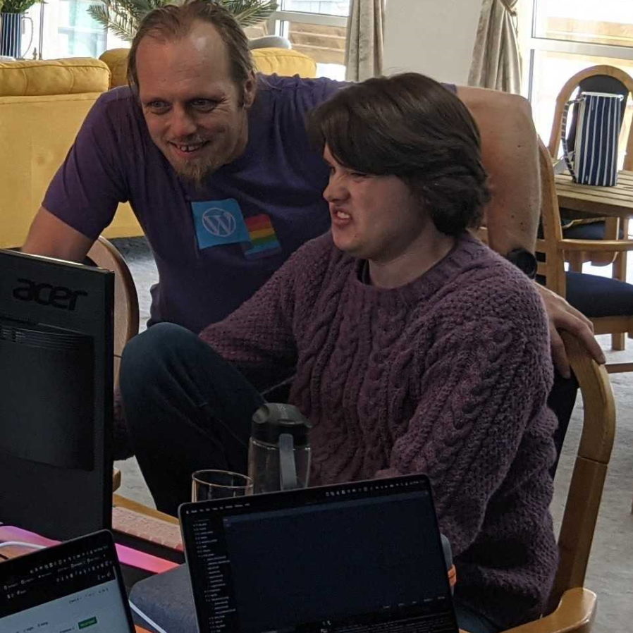 Dan and Jacob look at a piece of code together; Dan is smiling but Jacob looks disgusted.