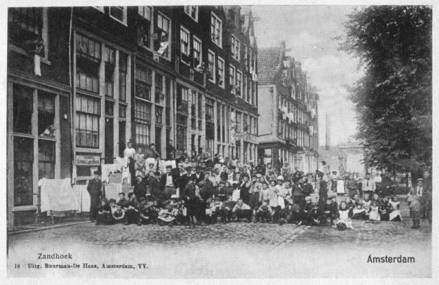 Pre-WWI Neighbourhood gathering in Amsterdam, with enormous windows (especially on the ground floor) visible.