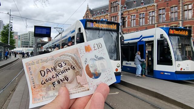 A £10 note with "Dan Q's Geocaching Fund" written on it in front of a number 13 tram.