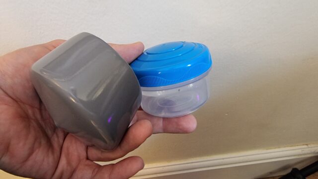 A small plastic screw-top tub and post topper; components for the geocache.