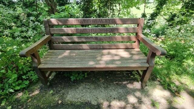 Memorial bench with inscription "In loving memory of Bill Mitchell 1934-2021"