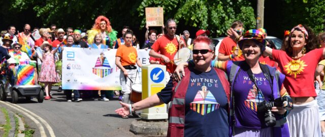 A Pride parade marches down a high street: Dan and his eldest can be seen in the very background.