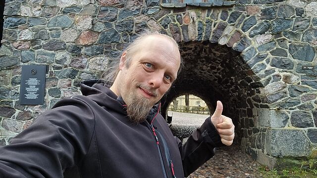 Dan throws a thumbs up outside a sea fort gateway.