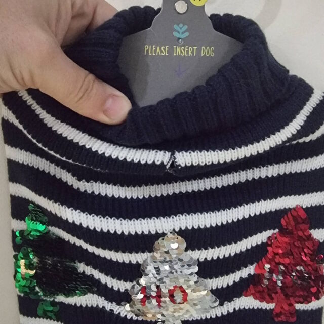 Christmas jumper for a dog, featuring blue-and-white stripes and sequin Christmas trees; its hanger contains an arrow pointing down alongside the text 'please insert dog'.