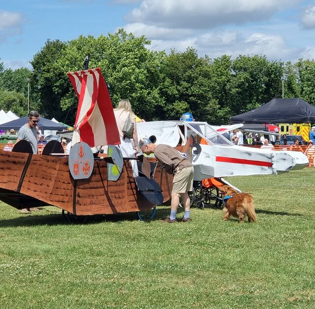 A cardboard longship collides with an X wing in a grassy field.