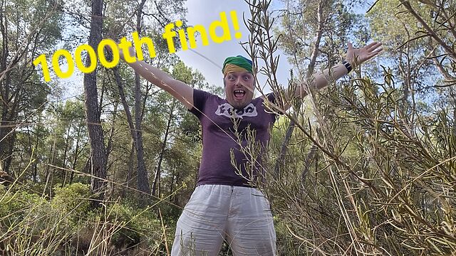 Dan - a white man wearing a rainbow-striped bandana - stands with his arms raised in celebration, alongside the superimposed words '1000th find'.